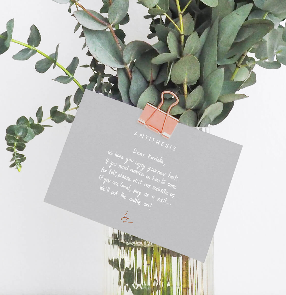 Branded card with handwritten massage hold on a flower vase by a copper pin