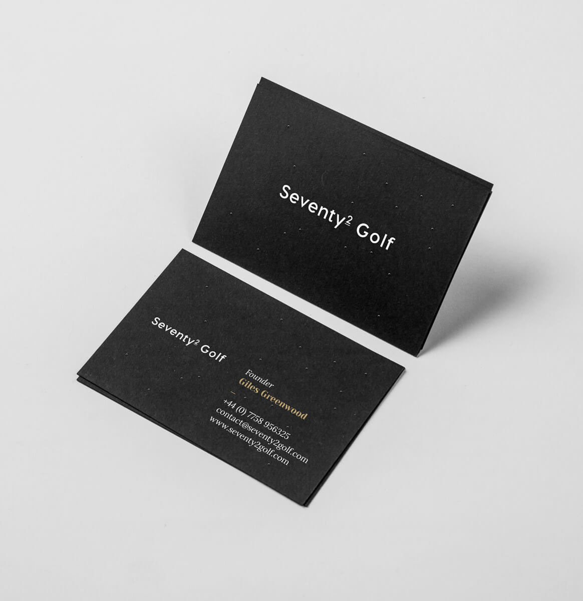 A few black business cards featuring the logo and contact details printed in white with a gold accent