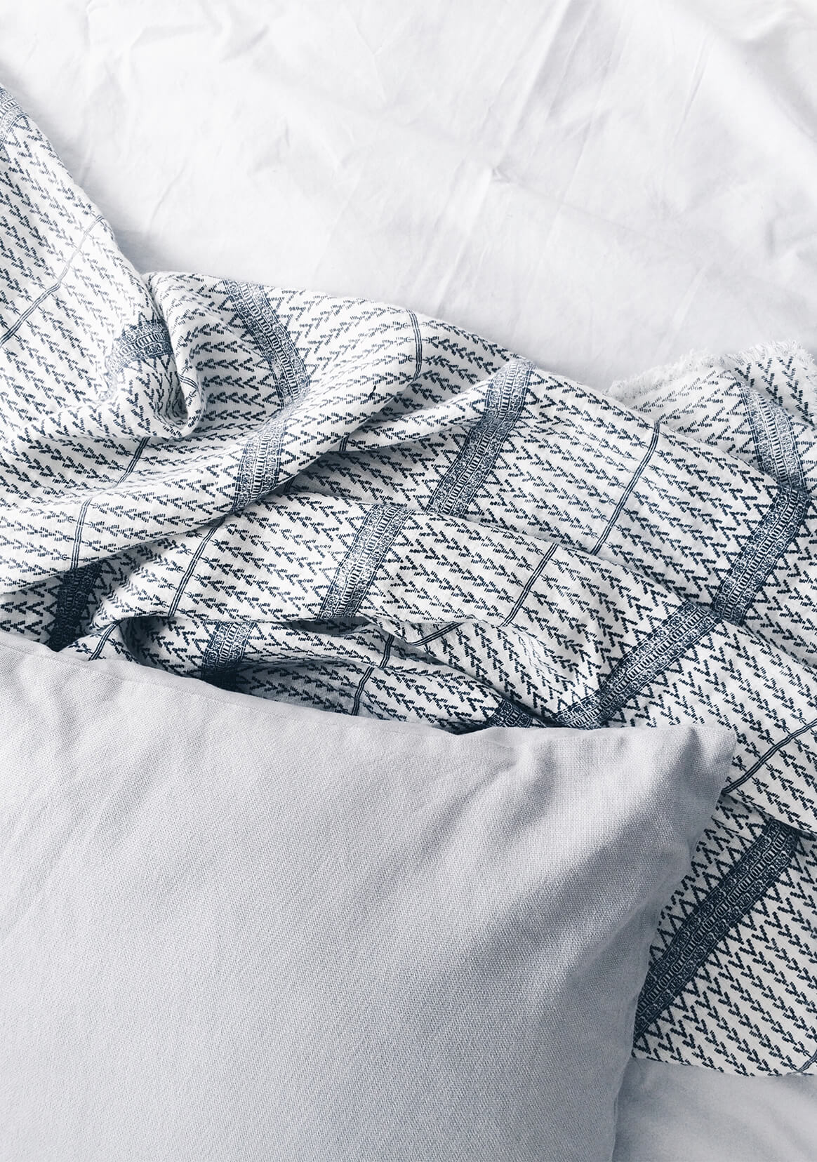 Grey bed sheets and cushion with patterned throw