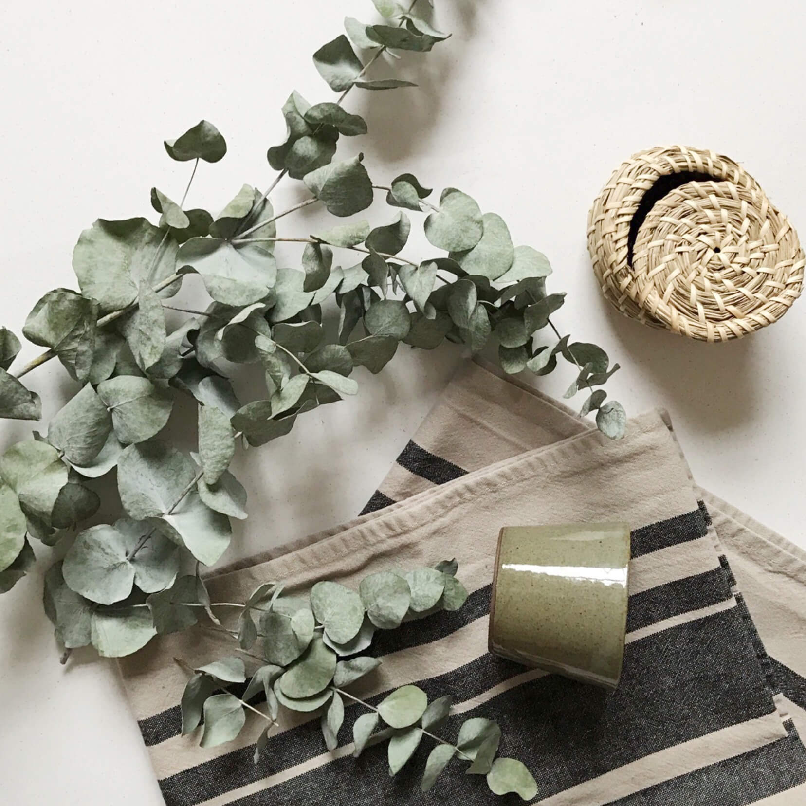 Eucalyptus leaves, folded table runner and cup on a table