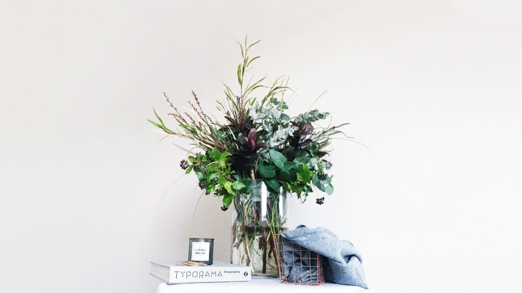 Bunch of greenery arranged in a vase with some props next to it