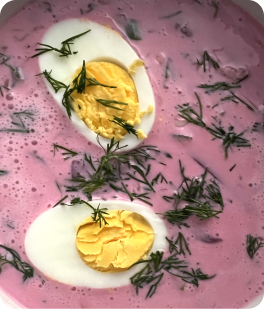 Close up of a plate of pink beetroot soup with eggs in it