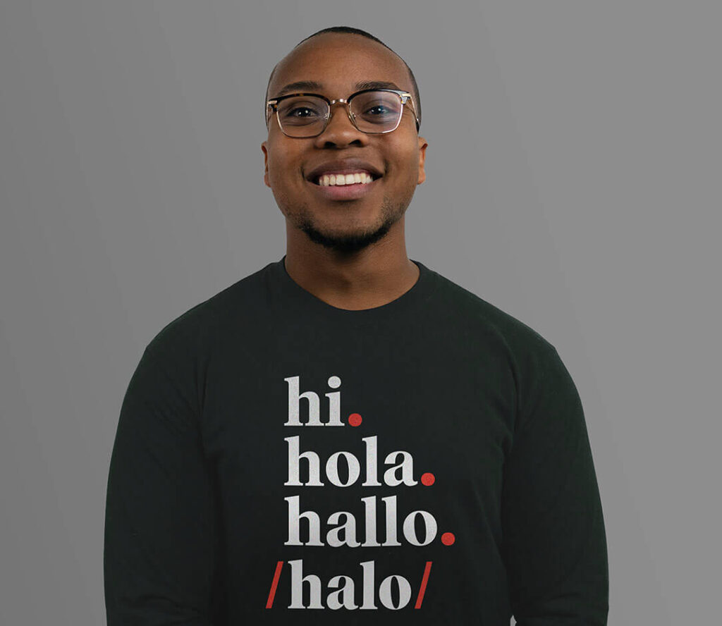 A men wearing a swater that says "Hi. Hola. Hallo. Halo."